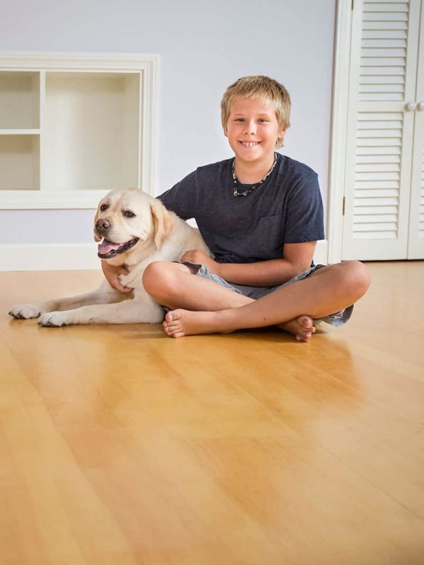 Boy and dog sitting on white pine flooring